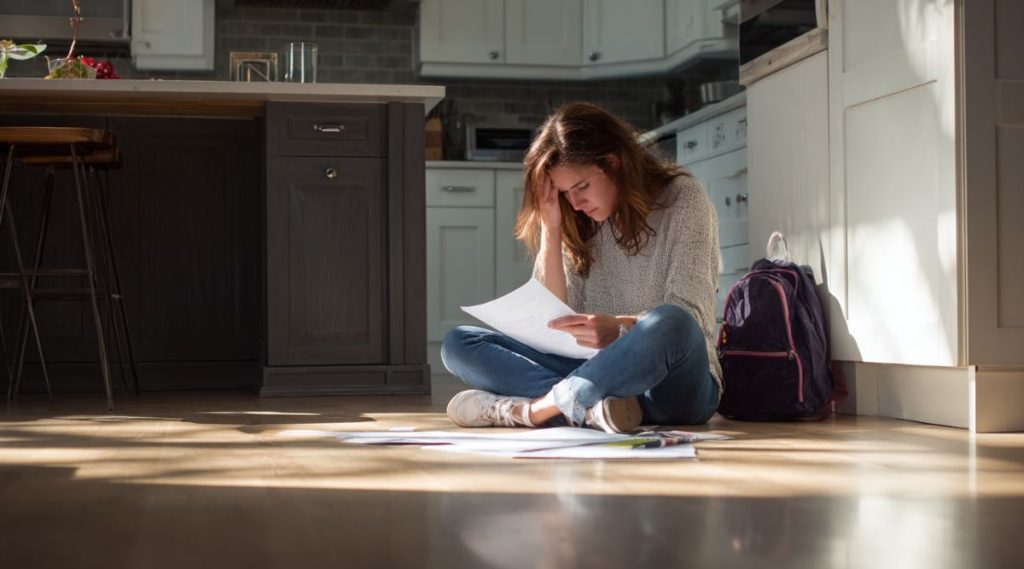 Woman seated on a kitchen floor holding court paperwork, representing enforcement of a Woburn court order