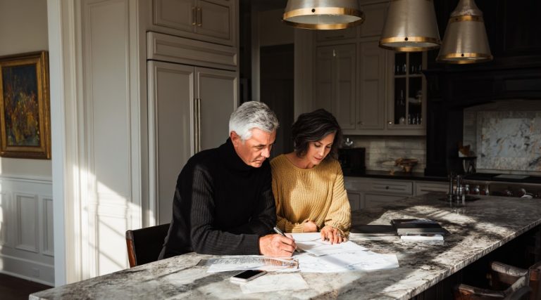 Couple writing on documents at a marble kitchen island, on how residency requirements differ between states