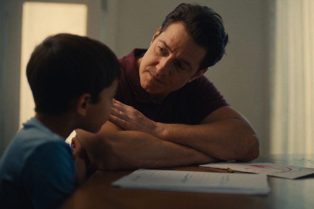 Father and young son seated across a table with paperwork between them, representing child support in a Massachusetts divorce