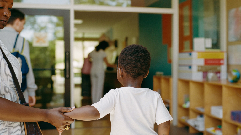 Parent at a bright New England daycare with insurance paperwork, health insurance and child care in a child support order