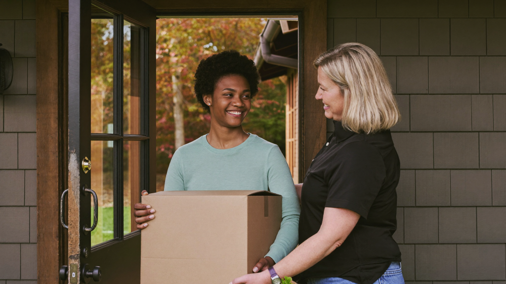 Young adult moving into a first apartment as a parent carries a box, when child support ends in Massachusetts
